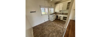 A kitchen with a tile floor and white appliances.