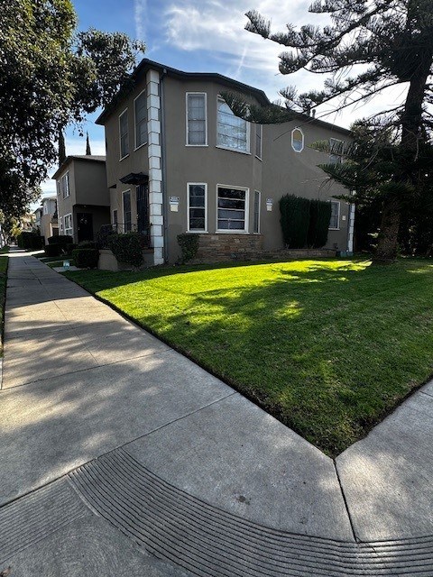 A house with a well-kept lawn and a sidewalk in front.
