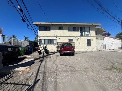 A red car is parked in front of a two-story building.