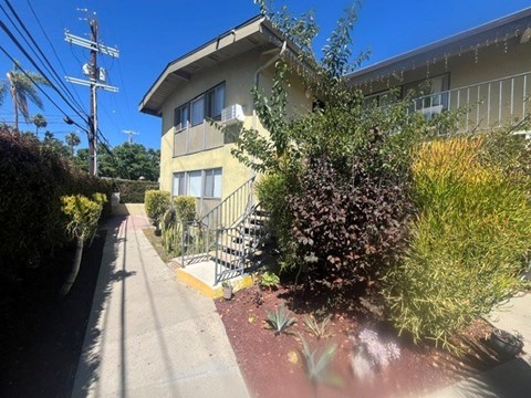 A residential building with a staircase and greenery in front.