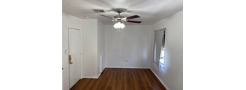 A room with a ceiling fan and wooden floors.