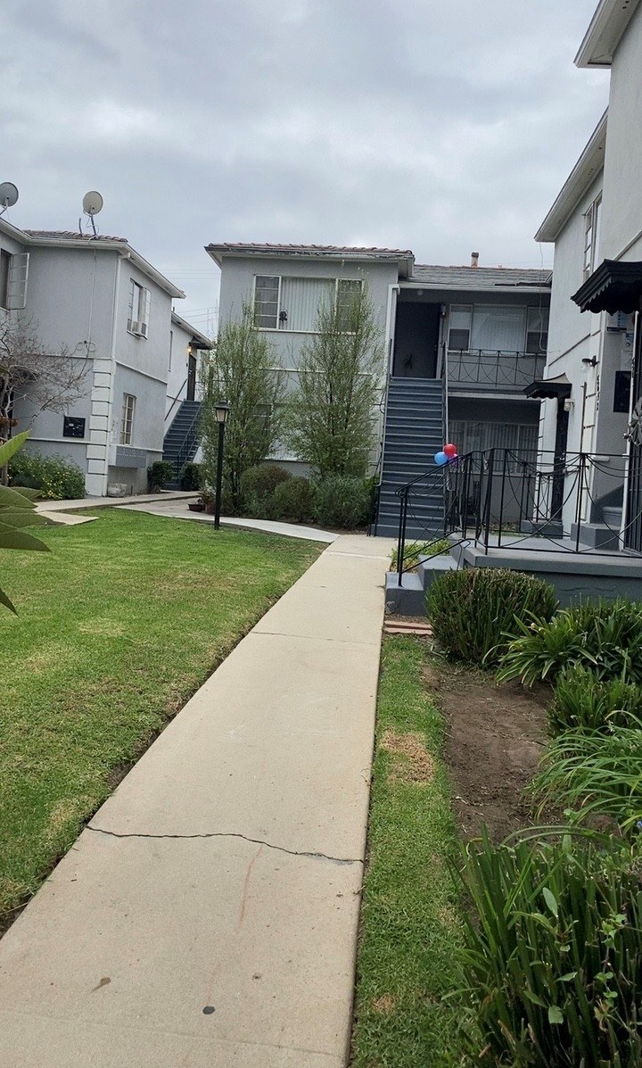 A concrete pathway leads to a house with a small garden.