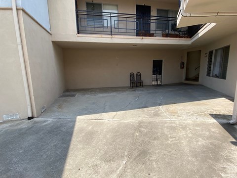 A balcony with a railing and chairs is on the second floor of a building.