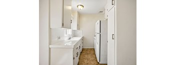 A white kitchen with a sink and a refrigerator.