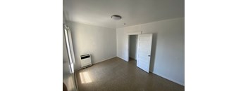 A room with a white door and a window with blinds.