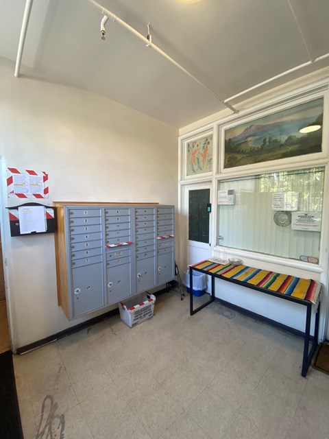 A room with a bench, a fridge, and a cabinet.