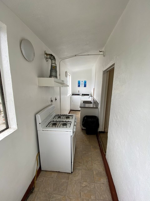 A white stove is in a narrow hallway.