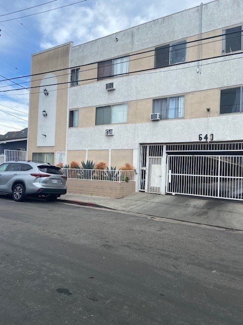 A car is parked in front of a building with the number 643 on it.