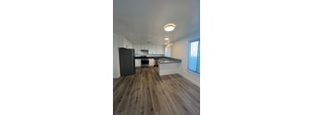 A kitchen with a black refrigerator and wooden floors.