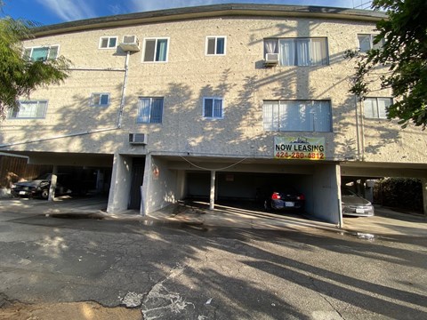 A building with a sign that says "NOW LEASING" and a phone number.