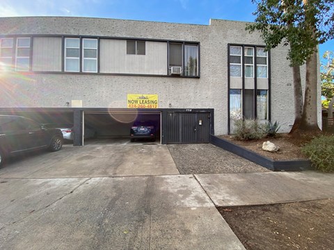 A building with a sign that says "NOW LEASING" and a phone number below it.