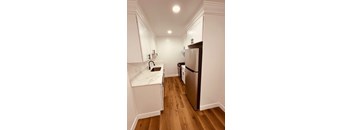 A kitchen with white cabinets and a refrigerator.