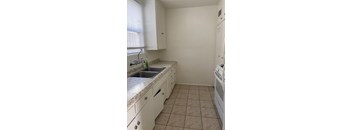 A kitchen with white cabinets and a tiled floor.