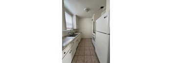 A kitchen with a white fridge, sink and cabinets.