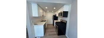 A kitchen with black appliances and white cabinets.