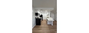 A kitchen with black appliances and white cabinets.