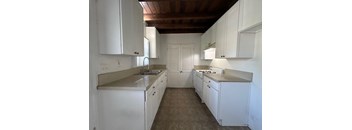 A kitchen with white cabinets and a wooden ceiling.