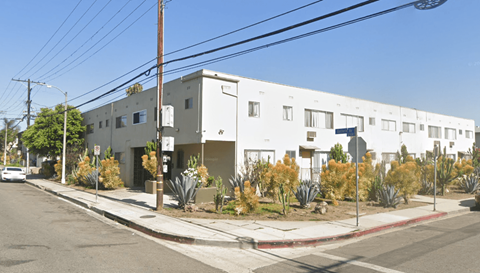 A white building with a red line on the sidewalk in front of it.