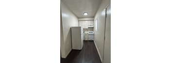 A kitchen with white appliances and wood floors.