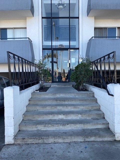 A set of concrete stairs leads to a glass door entrance.