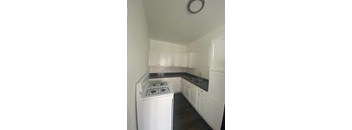 A small kitchen with a white stove and cabinets.