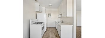 A white kitchen with a stove, oven, and sink.