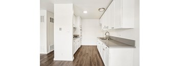A kitchen with white cabinets and a wooden floor.