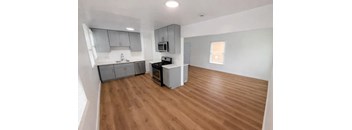 A kitchen with wooden floors and a microwave above the stove.