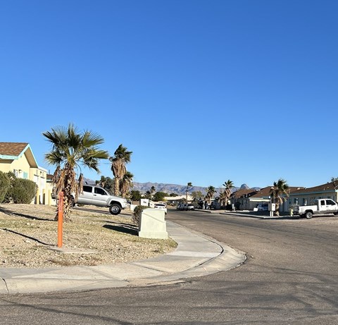 A residential street with houses and parked cars.