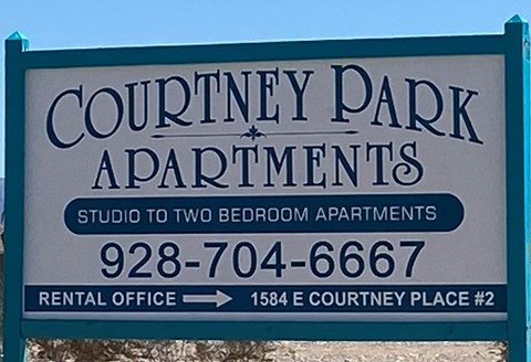 A sign for Courtney Park Apartments with a phone number and address for the rental office.