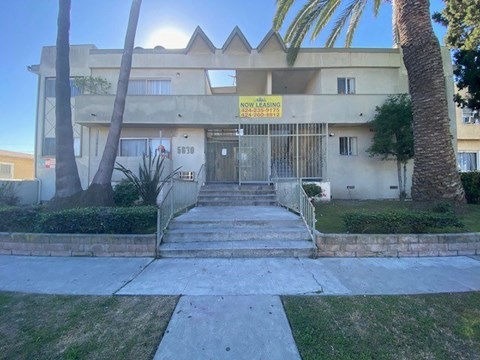 A building with a "NOW LEASING" sign in front of it.