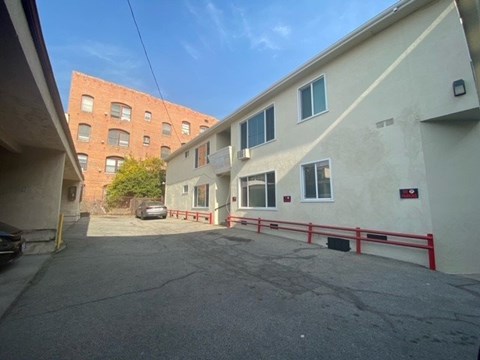 A parking lot in front of a building with a red fence.