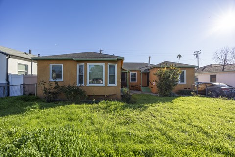 A yellow house with a green lawn in front.