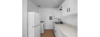 A kitchen with a white fridge, dishwasher and cabinets.
