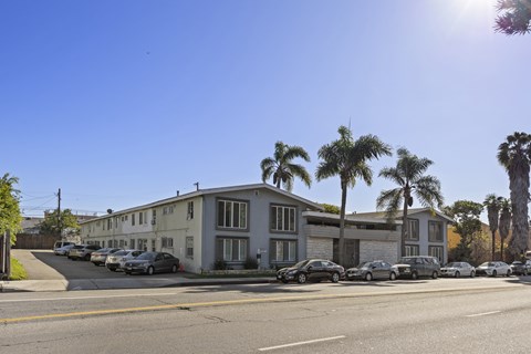 A sunny day in a residential area with apartment buildings and parked cars.