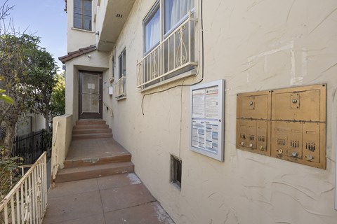 A white building with a brown door and a sign on the wall.