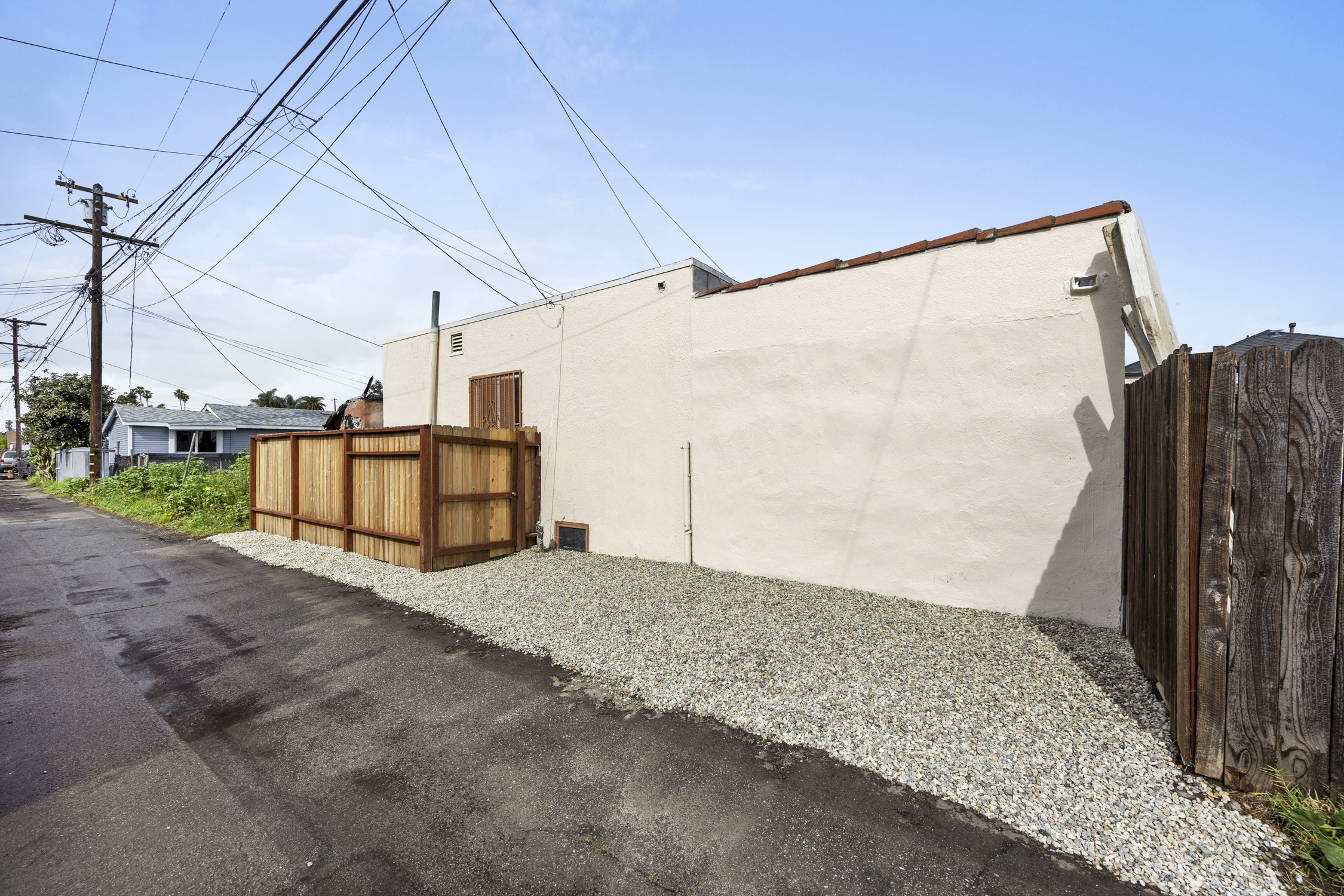 A white building with a brown door and a wooden fence.
