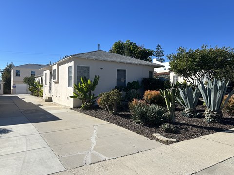 A white house with a grey roof and a driveway in front.