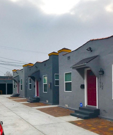 A series of grey houses with red doors and windows.