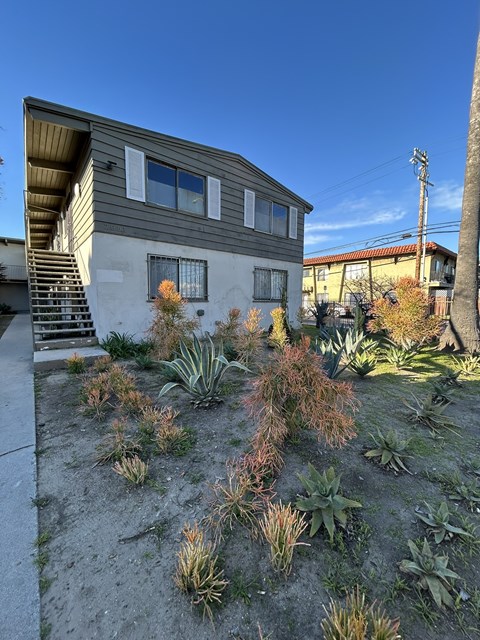 A house with a grey siding and a brown roof with a staircase leading up to the entrance.