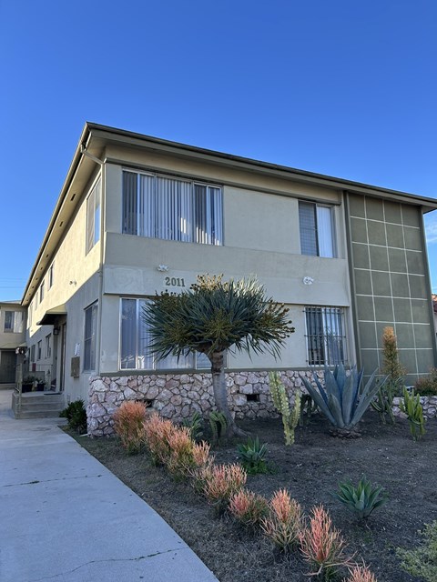 A house with a stone wall and a cactus garden in front.