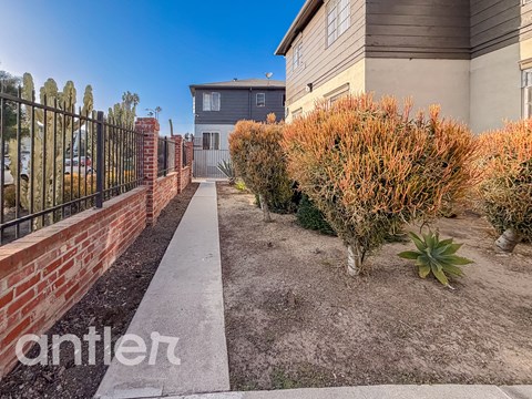 A residential area with a house, a fence, and a sidewalk.