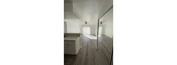 A kitchen with white cabinets and a wooden floor.