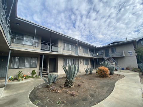 A concrete building with a balcony and a small garden in front.