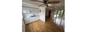 A kitchen with white cabinets and a wooden floor.