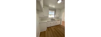 A kitchen with white cabinets and a wooden floor.