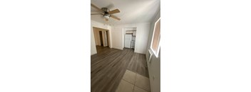 A room with a ceiling fan and a refrigerator.
