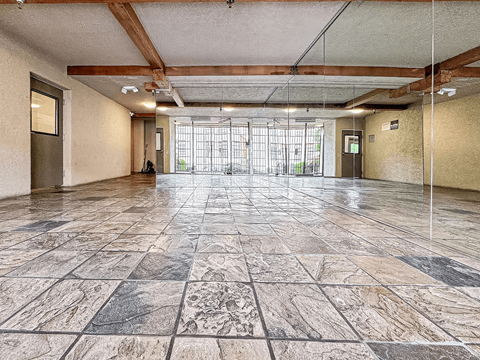 A large, empty room with marble flooring and wooden beams on the ceiling.