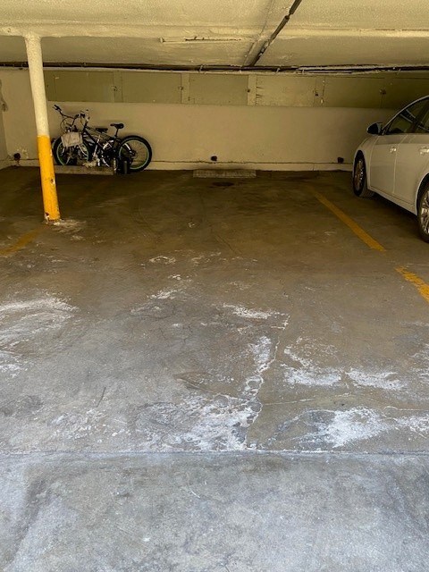 A white car is parked in a garage next to a bicycle.