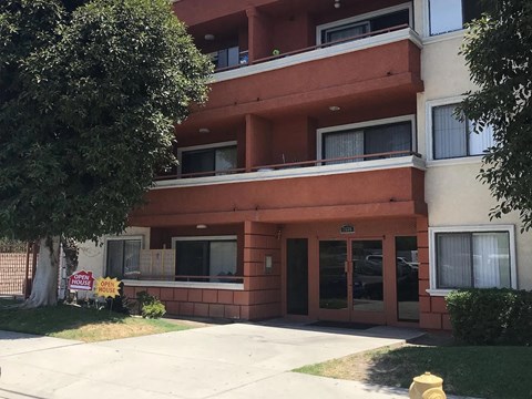 A multi-story apartment building with a "For Rent" sign in front.